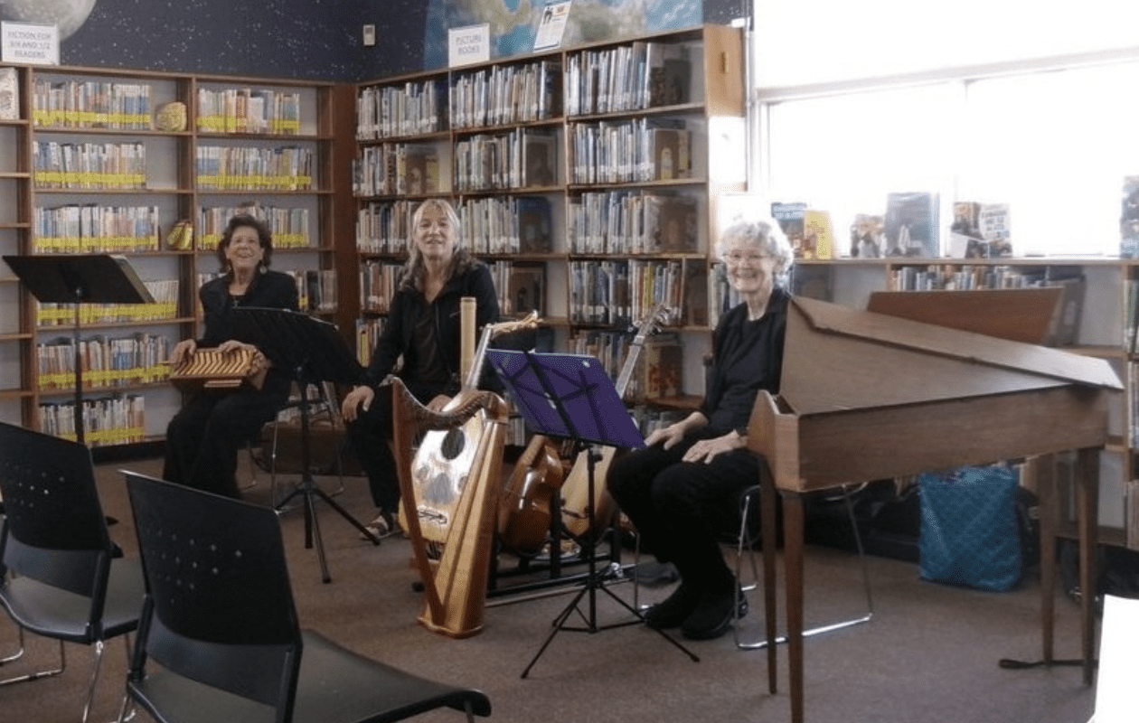 three women sitting with instruments in a library